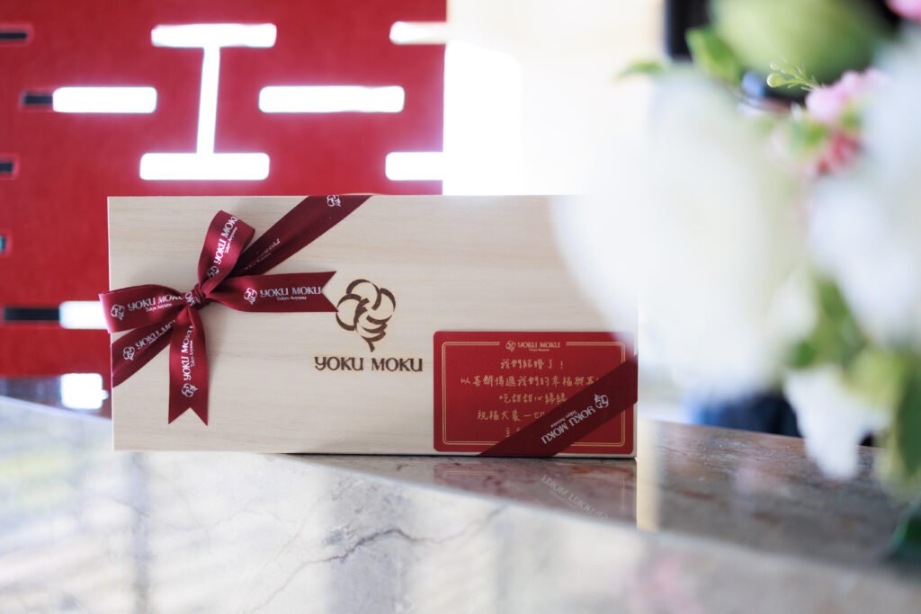 A wooden box of Taiwanese wedding cookies with a red announcement card, against a double happiness backdrop