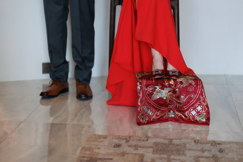 A bride in a red gown stands on an embroidered phoenix cushion beside the groom at a Taiwanese engagement ceremony